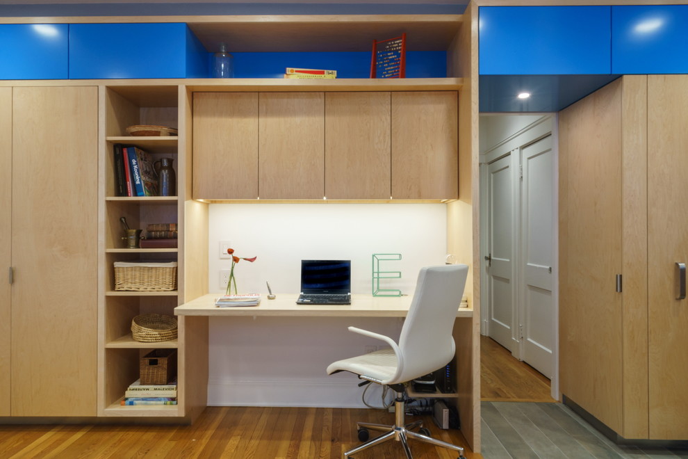 Ejemplo de despacho actual de tamaño medio con paredes blancas, suelo de madera en tonos medios y escritorio empotrado