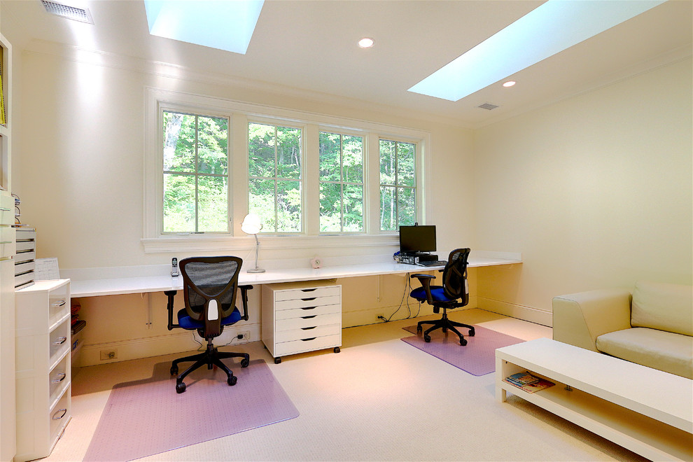 На фото: рабочее место в стиле неоклассика (современная классика) с белыми стенами, ковровым покрытием и встроенным рабочим столом