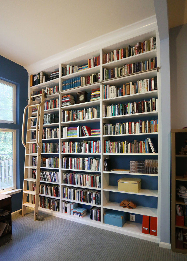 На фото: большой домашняя библиотека в стиле неоклассика (современная классика) с синими стенами, ковровым покрытием, встроенным рабочим столом и серым полом без камина с