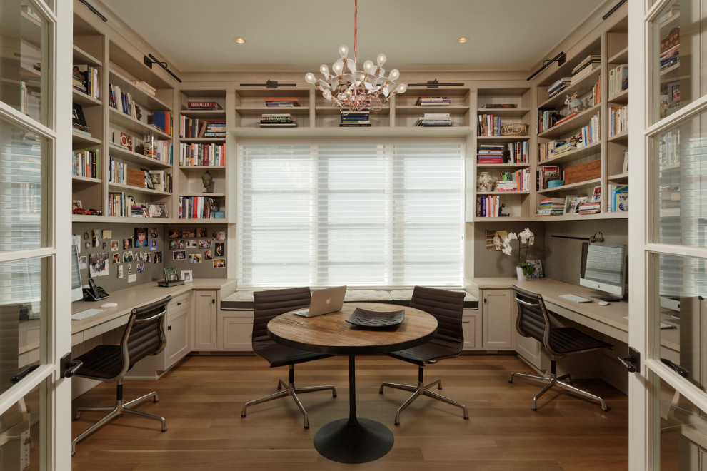 This is an example of a traditional home office in DC Metro with beige walls, medium hardwood flooring, a built-in desk and brown floors.