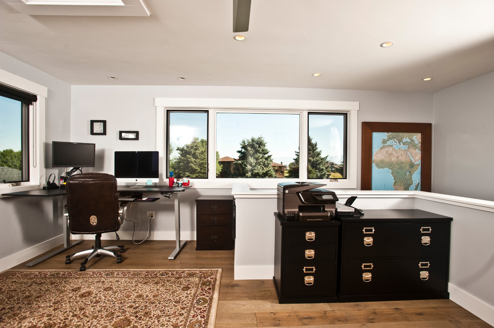 Idee per un grande ufficio minimal con pareti grigie, pavimento in legno massello medio, scrivania autoportante e pavimento marrone