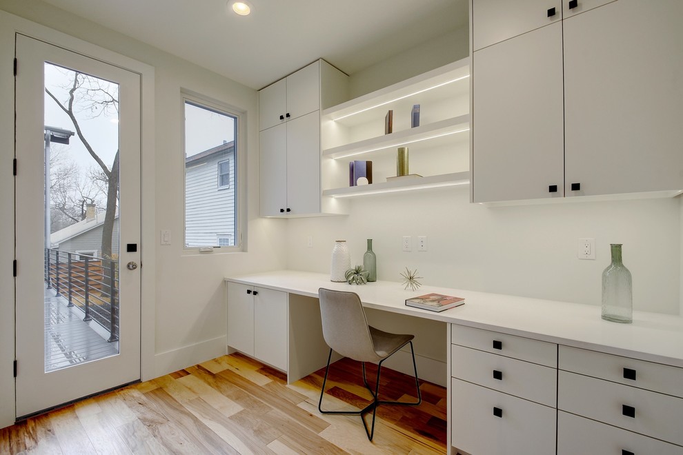 Esempio di uno studio design con pareti bianche, pavimento in legno massello medio, scrivania incassata e pavimento marrone