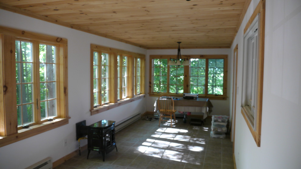 Imagen de despacho de estilo de casa de campo de tamaño medio con paredes blancas, estufa de leña y escritorio independiente