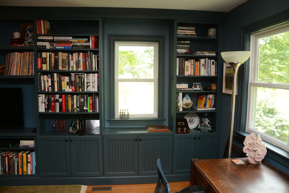 Imagen de despacho tradicional de tamaño medio sin chimenea con biblioteca, paredes azules, suelo de madera clara, escritorio independiente y suelo marrón