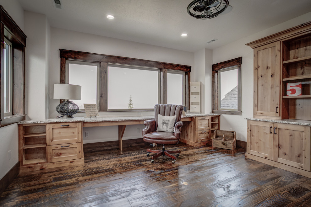 Diseño de despacho rústico de tamaño medio con paredes blancas, suelo de madera oscura y escritorio empotrado
