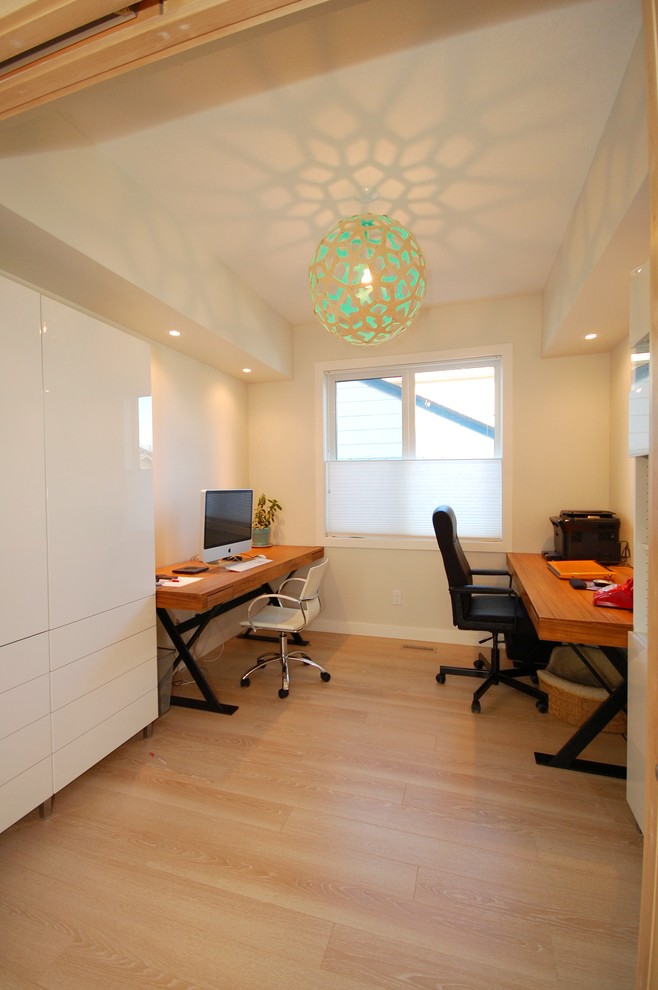 Modernes Arbeitszimmer ohne Kamin mit beiger Wandfarbe, hellem Holzboden und Einbau-Schreibtisch in Edmonton