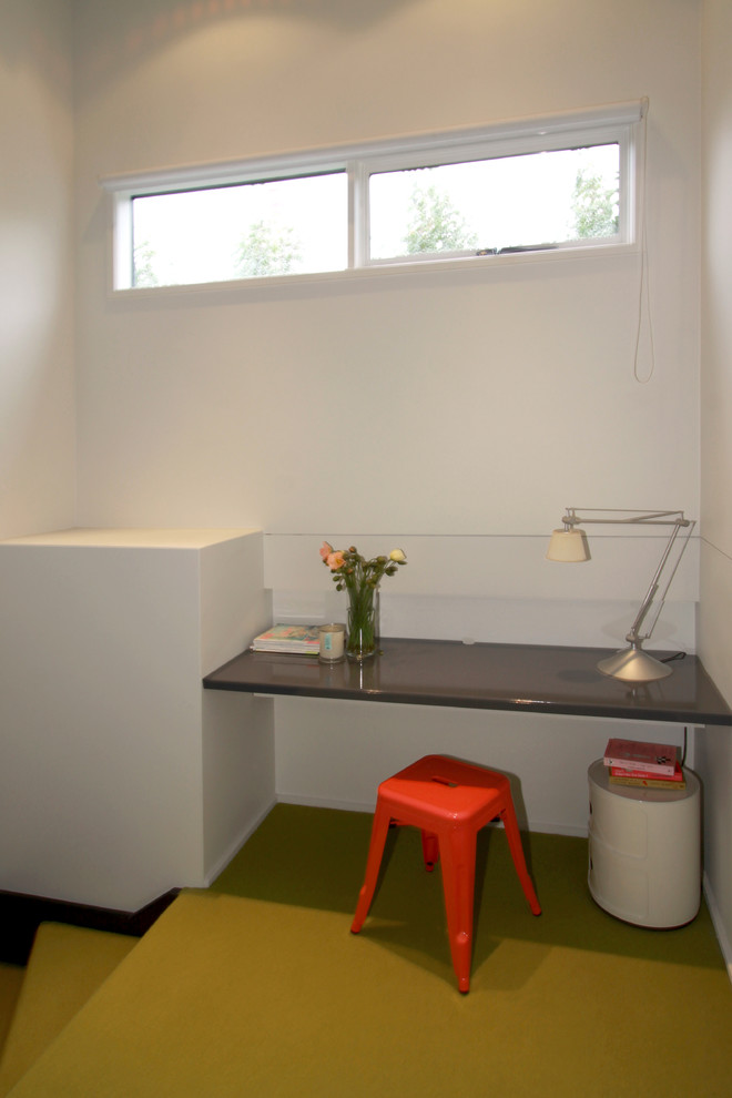 Diseño de despacho minimalista sin chimenea con paredes blancas, moqueta, escritorio empotrado y suelo amarillo
