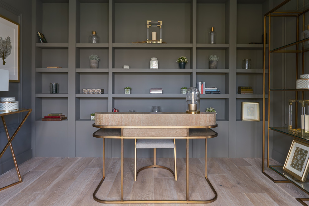 Ejemplo de despacho actual sin chimenea con paredes grises, suelo de madera clara, escritorio independiente y suelo beige