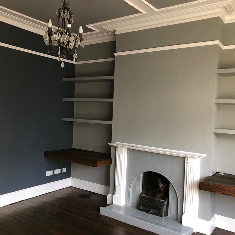 ロンドンにある高級な中くらいなコンテンポラリースタイルのおしゃれな書斎 (青い壁、塗装フローリング、標準型暖炉、タイルの暖炉まわり、造り付け机、茶色い床) の写真