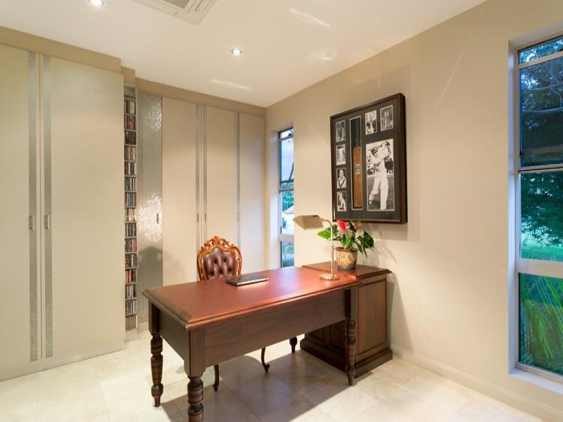 This is an example of a large modern study in Brisbane with white walls, travertine flooring, no fireplace, a freestanding desk and multi-coloured floors.