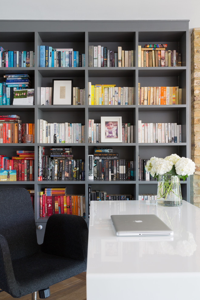Idéer för funkis hemmabibliotek, med grå väggar, mellanmörkt trägolv och ett fristående skrivbord