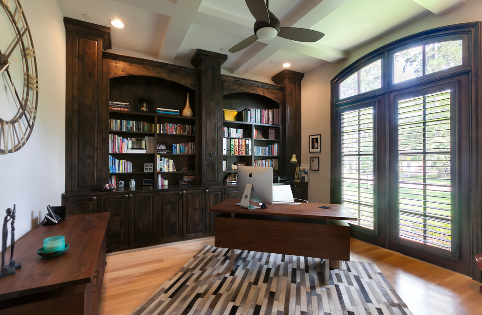 Inredning av ett klassiskt stort hemmabibliotek, med grå väggar, ljust trägolv och ett fristående skrivbord