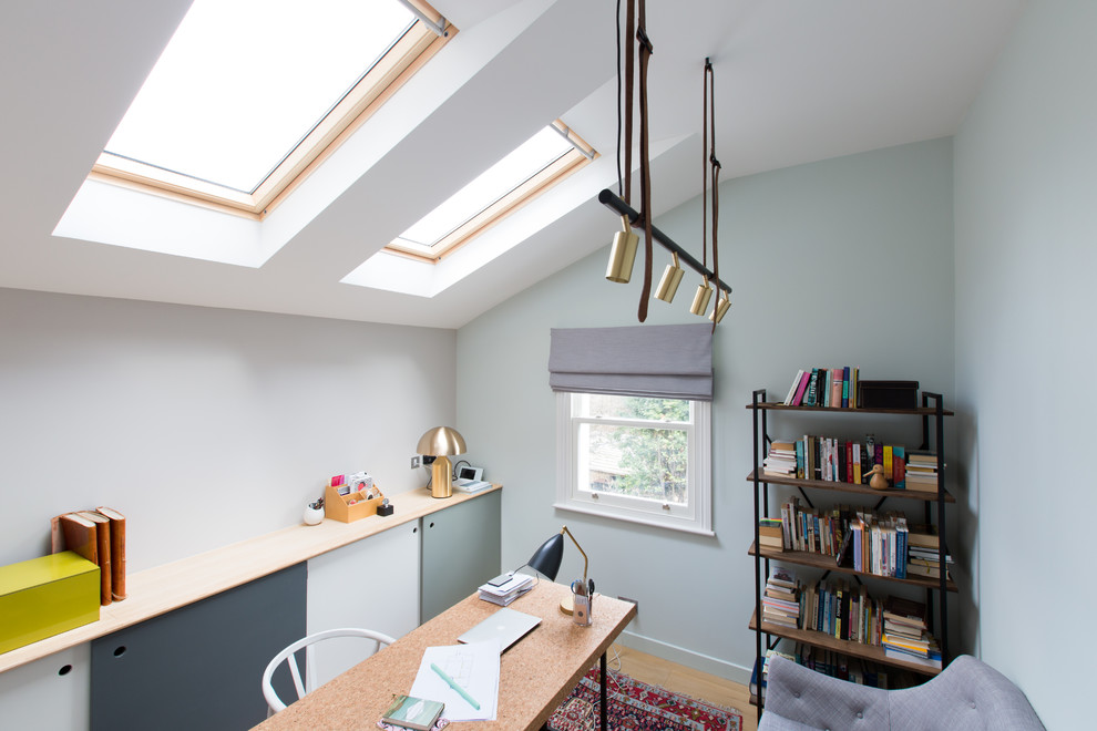 Nordisk inredning av ett mellanstort hemmabibliotek, med gröna väggar, ljust trägolv och ett fristående skrivbord