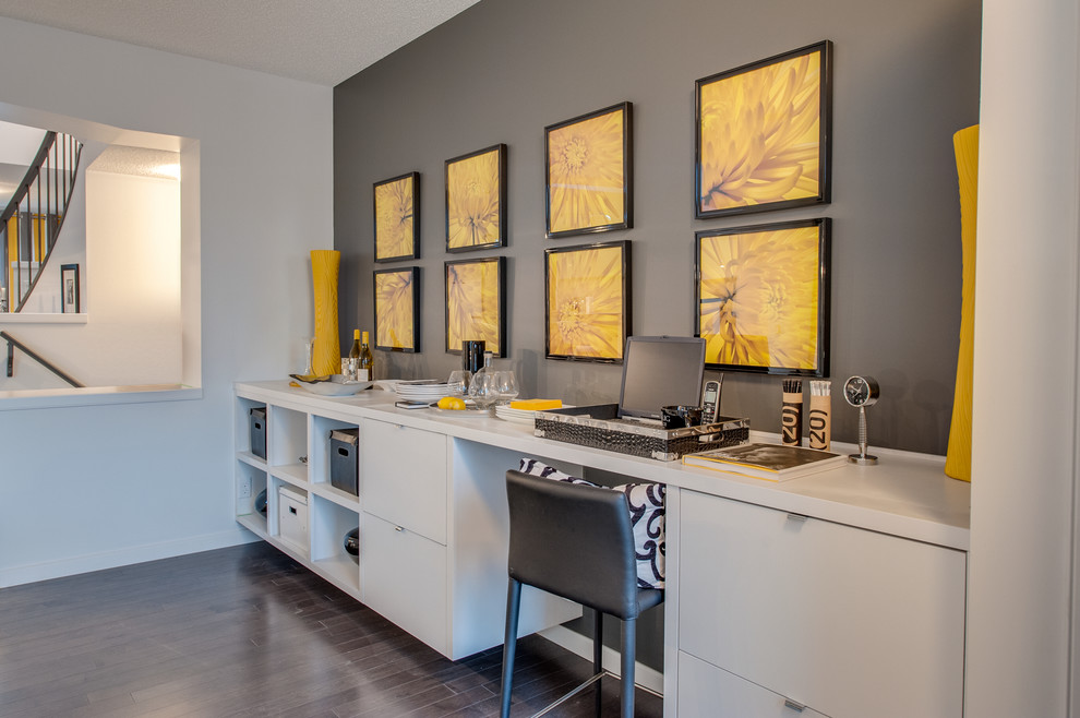 Modernes Arbeitszimmer mit grauer Wandfarbe, dunklem Holzboden und Einbau-Schreibtisch in Calgary
