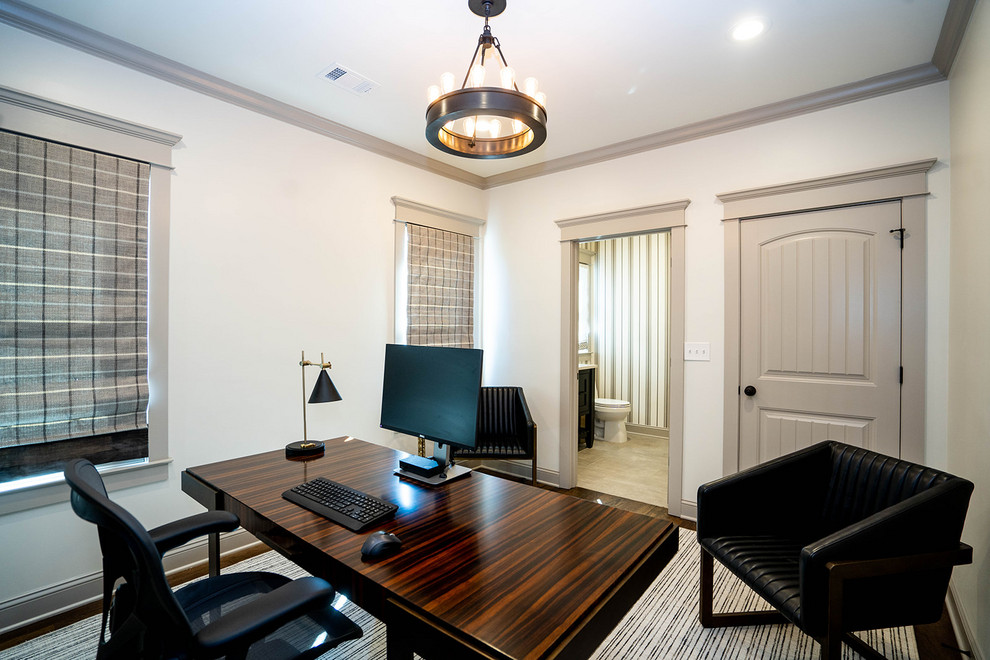 Ejemplo de despacho actual de tamaño medio sin chimenea con paredes beige, suelo de madera en tonos medios, escritorio independiente y suelo marrón