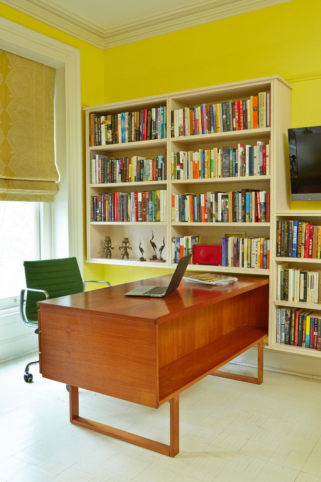 Immagine di uno studio chic con pareti gialle, pavimento in legno verniciato e scrivania autoportante