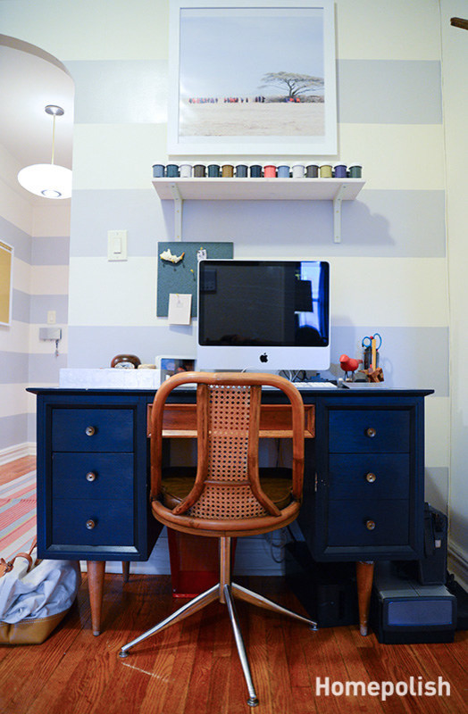 Bild på ett litet 50 tals arbetsrum, med grå väggar, mellanmörkt trägolv och ett fristående skrivbord