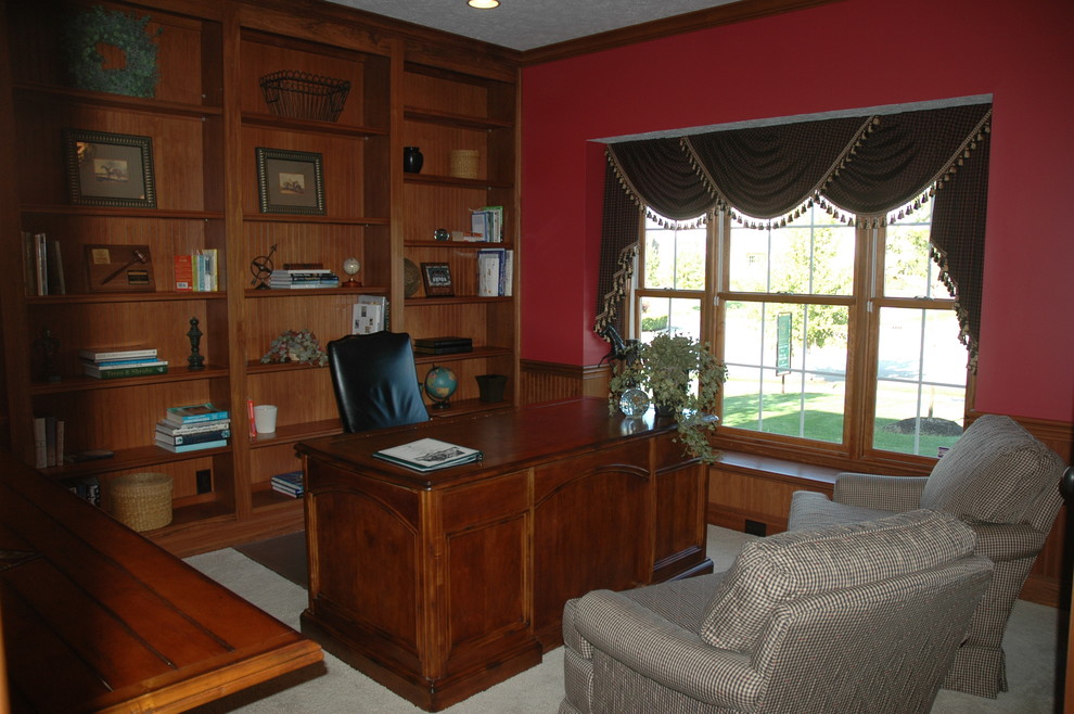 Aménagement d'un bureau classique avec un mur rouge, moquette et un bureau indépendant.