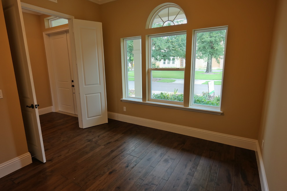 Ejemplo de despacho actual grande con paredes beige y suelo de madera en tonos medios