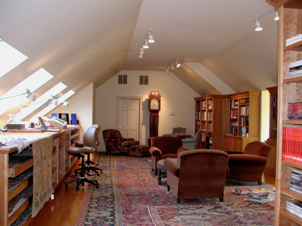 Inredning av ett klassiskt stort hemmastudio, med vita väggar, ljust trägolv, ett inbyggt skrivbord och brunt golv