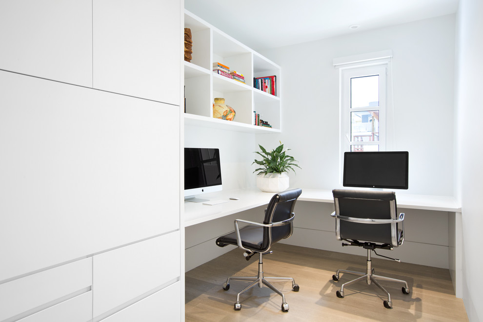 Modelo de despacho contemporáneo de tamaño medio con paredes blancas, escritorio empotrado, suelo de madera clara y suelo beige