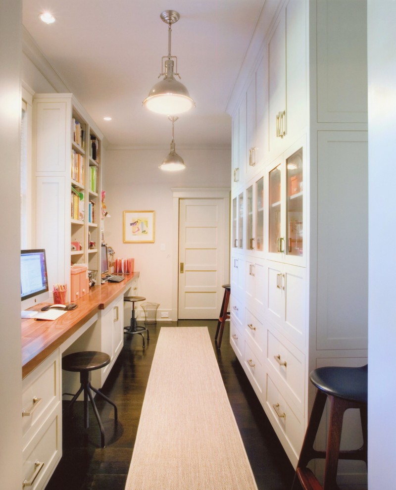 Klassisk inredning av ett litet arbetsrum, med vita väggar, mörkt trägolv och ett inbyggt skrivbord