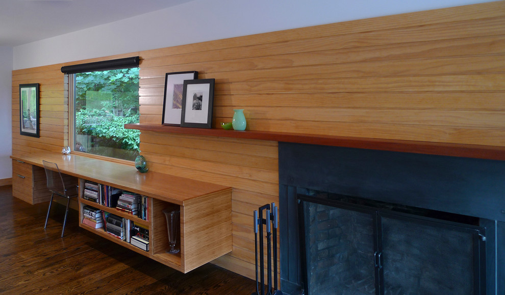 Cette image montre un bureau design de taille moyenne avec un mur blanc, un sol en bois brun, une cheminée standard, un manteau de cheminée en métal, un bureau intégré et un sol marron.