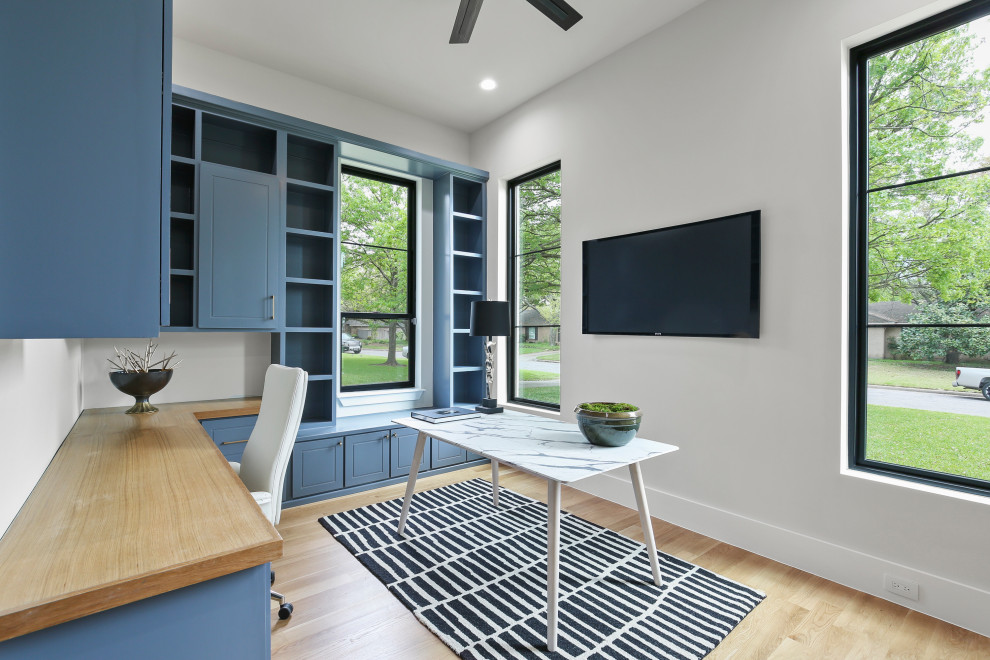 Modelo de despacho minimalista de tamaño medio con paredes blancas, suelo de madera clara y escritorio empotrado