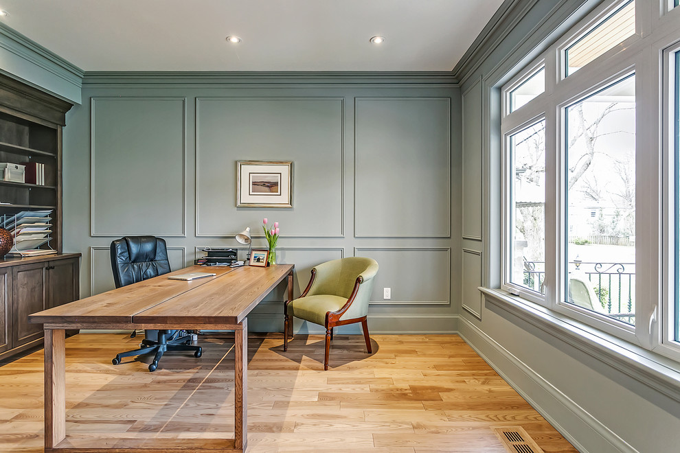 Foto de despacho tradicional renovado de tamaño medio sin chimenea con paredes grises, suelo de madera clara y escritorio independiente