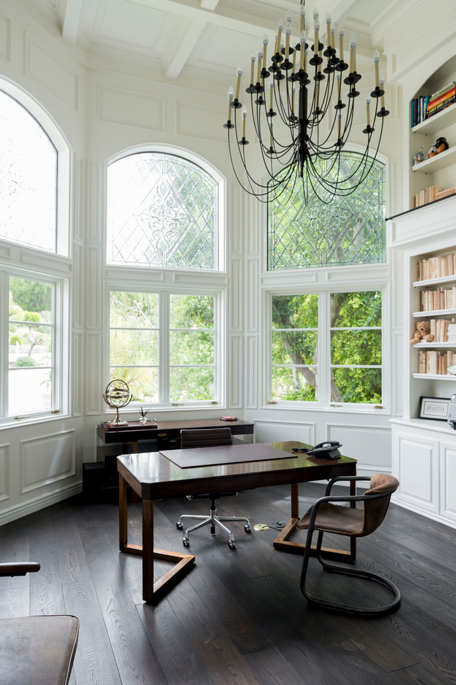 Modelo de despacho tradicional renovado de tamaño medio sin chimenea con paredes blancas, suelo de madera oscura, escritorio independiente y suelo marrón