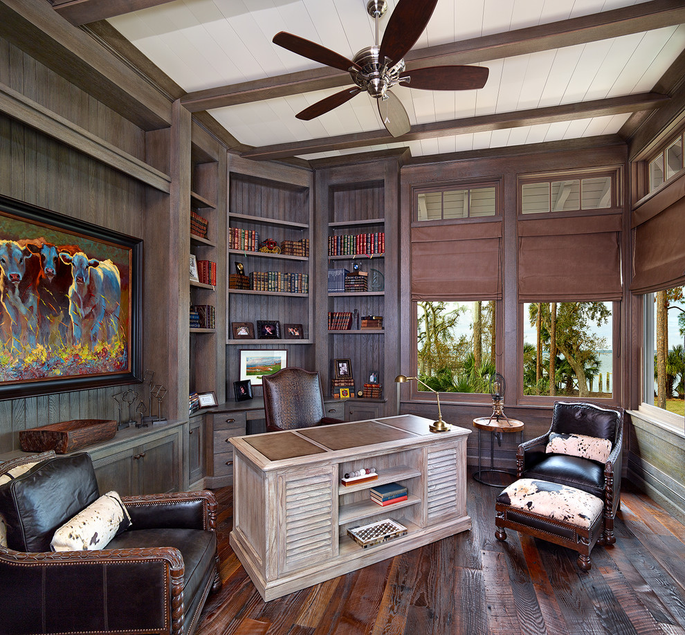 This is an example of a beach style study in Other with brown walls, dark hardwood flooring, a freestanding desk and brown floors.
