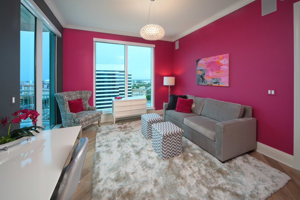 Diseño de despacho contemporáneo con paredes rosas, escritorio independiente y suelo de madera en tonos medios