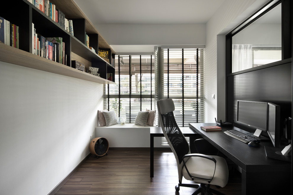 Inredning av ett modernt arbetsrum, med vita väggar, mellanmörkt trägolv, ett fristående skrivbord och brunt golv