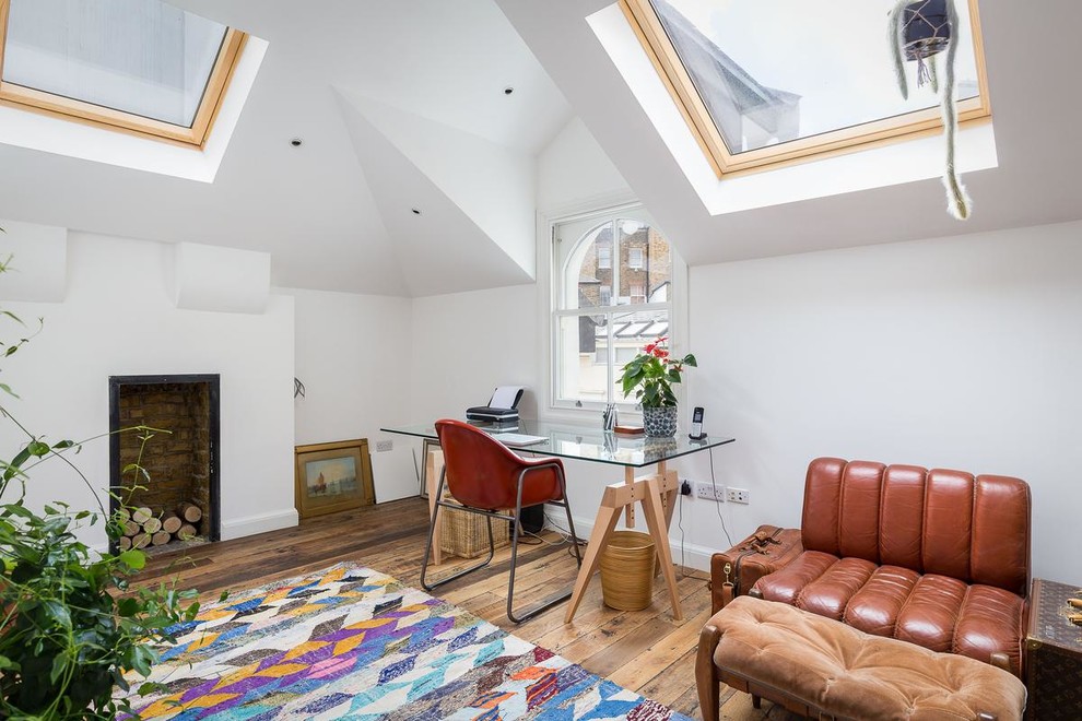Stilmix Arbeitszimmer mit weißer Wandfarbe, braunem Holzboden, Kamin, freistehendem Schreibtisch und braunem Boden in London