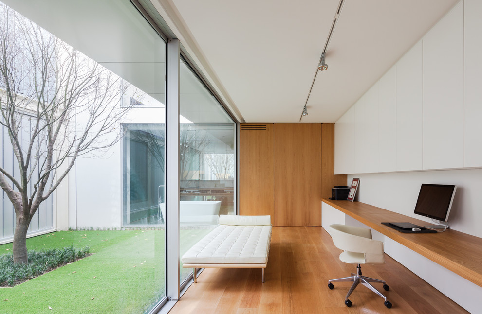 Ispirazione per un ufficio moderno con pareti bianche, pavimento in legno massello medio, scrivania incassata e pavimento marrone