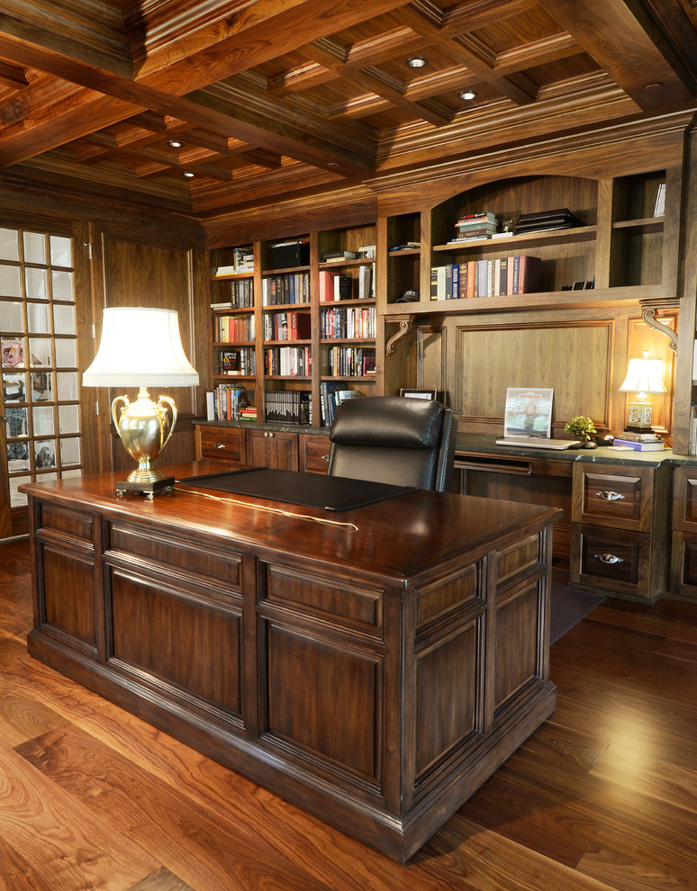 Diseño de despacho de estilo americano de tamaño medio sin chimenea con biblioteca, paredes marrones, suelo de madera en tonos medios, escritorio independiente y suelo marrón