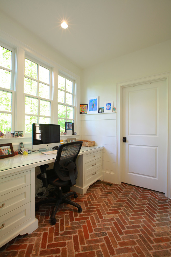Example of a classic built-in desk brick floor home office design in Atlanta with white walls