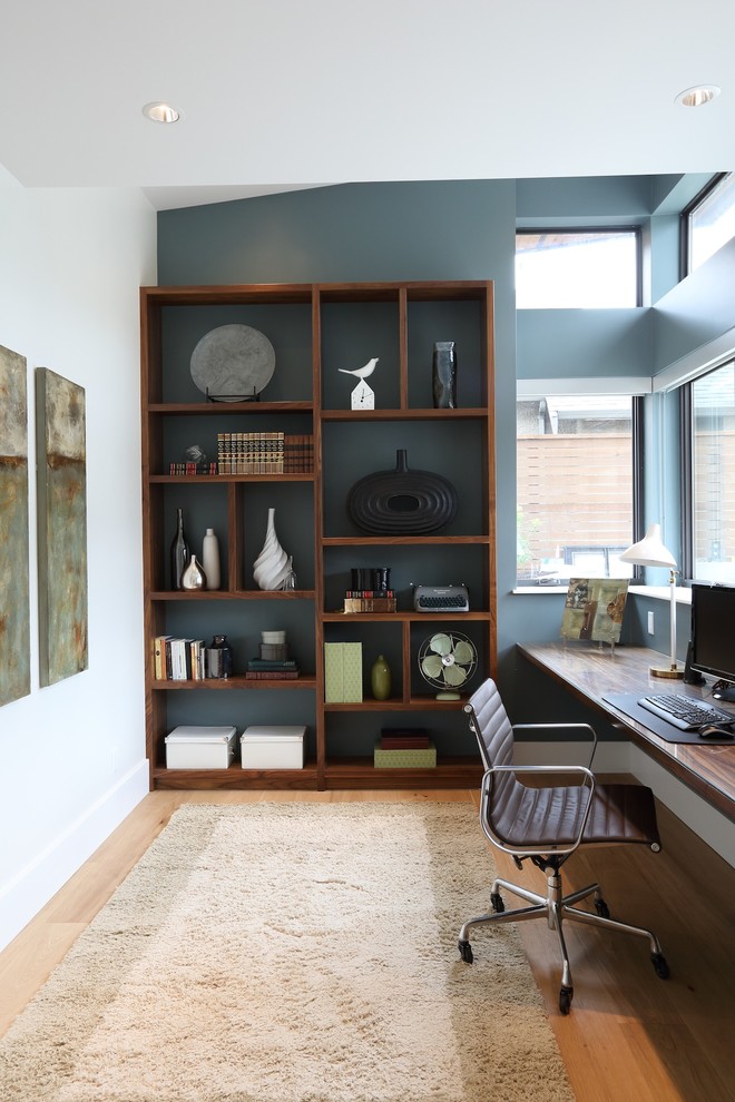 Imagen de despacho actual grande sin chimenea con paredes azules, suelo de madera clara y escritorio empotrado