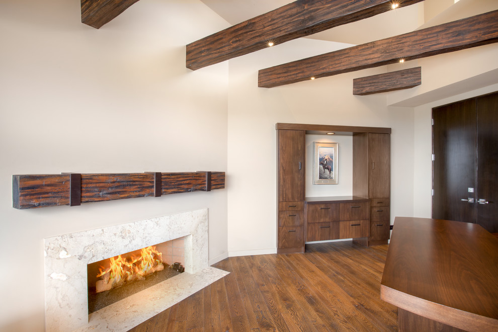 Example of a trendy freestanding desk medium tone wood floor study room design in Phoenix with beige walls, a standard fireplace and a stone fireplace