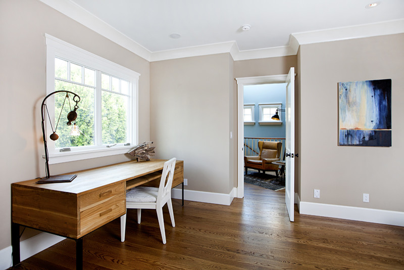 Modelo de despacho actual de tamaño medio sin chimenea con paredes beige, suelo de madera en tonos medios y suelo marrón