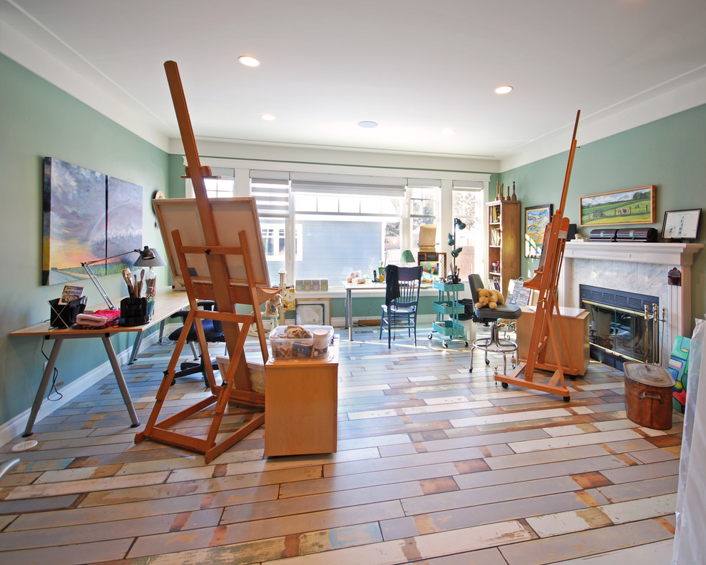 Immagine di una grande stanza da lavoro tradizionale con pareti verdi, pavimento in legno verniciato, camino classico, cornice del camino in pietra e scrivania autoportante