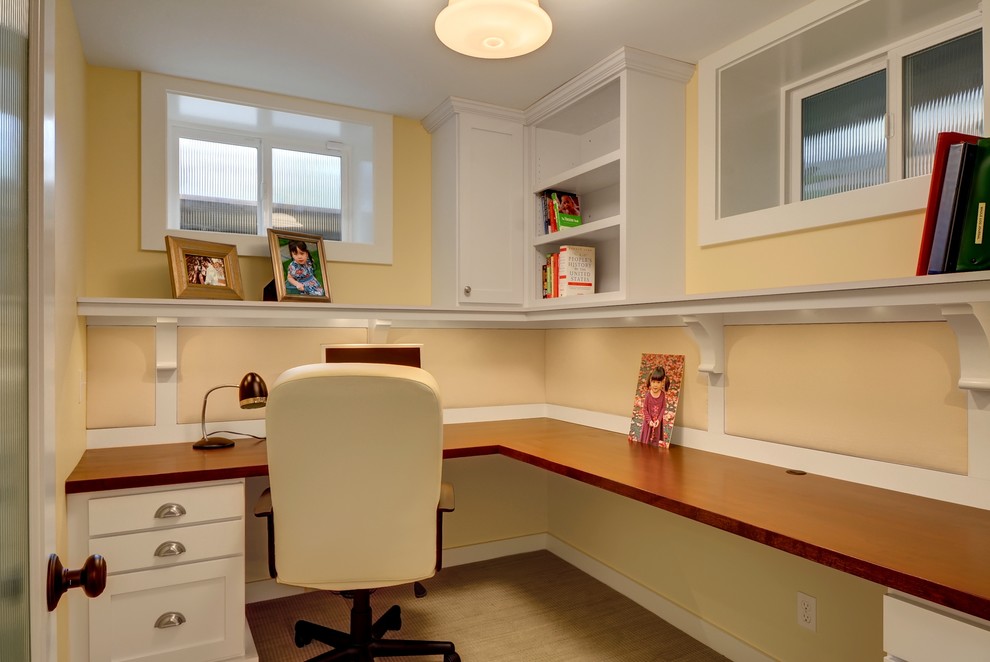 Diseño de despacho de estilo americano con paredes amarillas, moqueta y escritorio empotrado