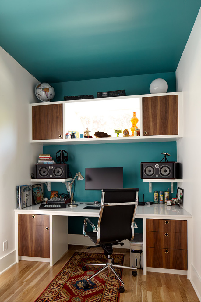 Esempio di uno studio minimal con pavimento in legno massello medio, scrivania incassata, pareti blu e pavimento marrone