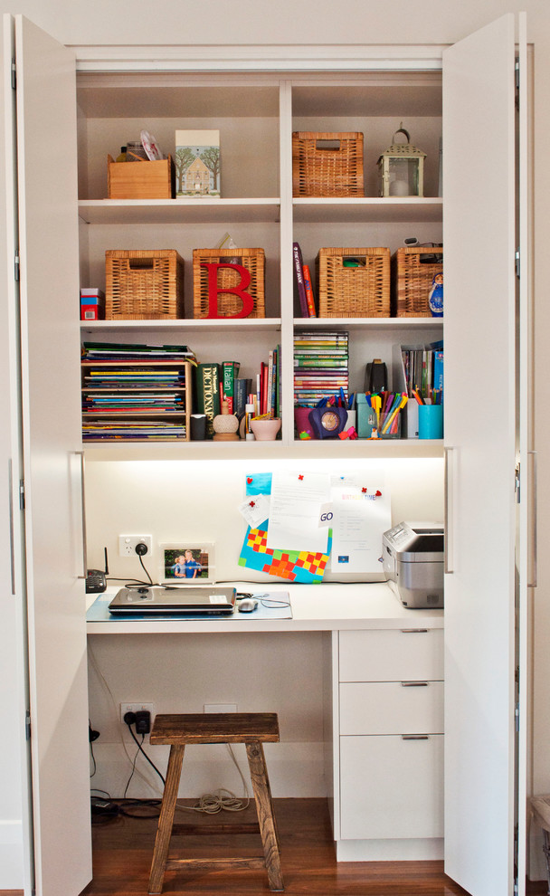 Inspiration for a small contemporary built-in desk medium tone wood floor home office remodel in Melbourne with white walls