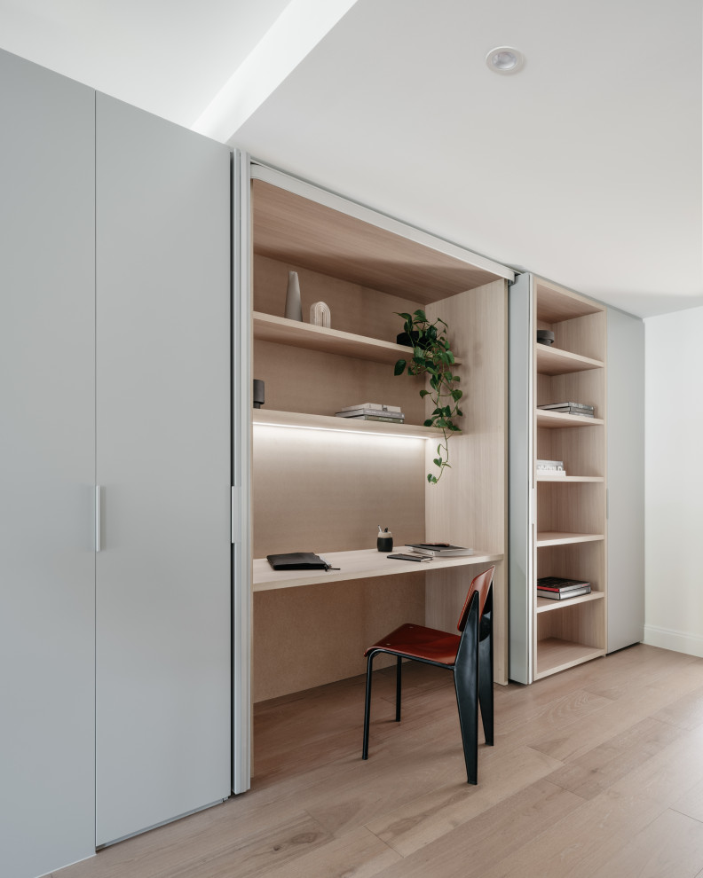 Cette image montre un bureau minimaliste avec un mur blanc, parquet clair, un bureau intégré et un sol beige.