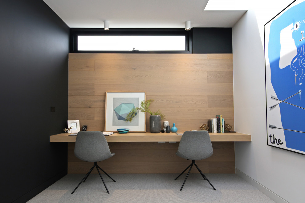Diseño de despacho contemporáneo con paredes negras, moqueta, escritorio empotrado y suelo gris