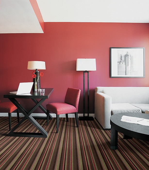 Modelo de despacho minimalista pequeño con paredes rojas, moqueta, escritorio independiente y suelo multicolor