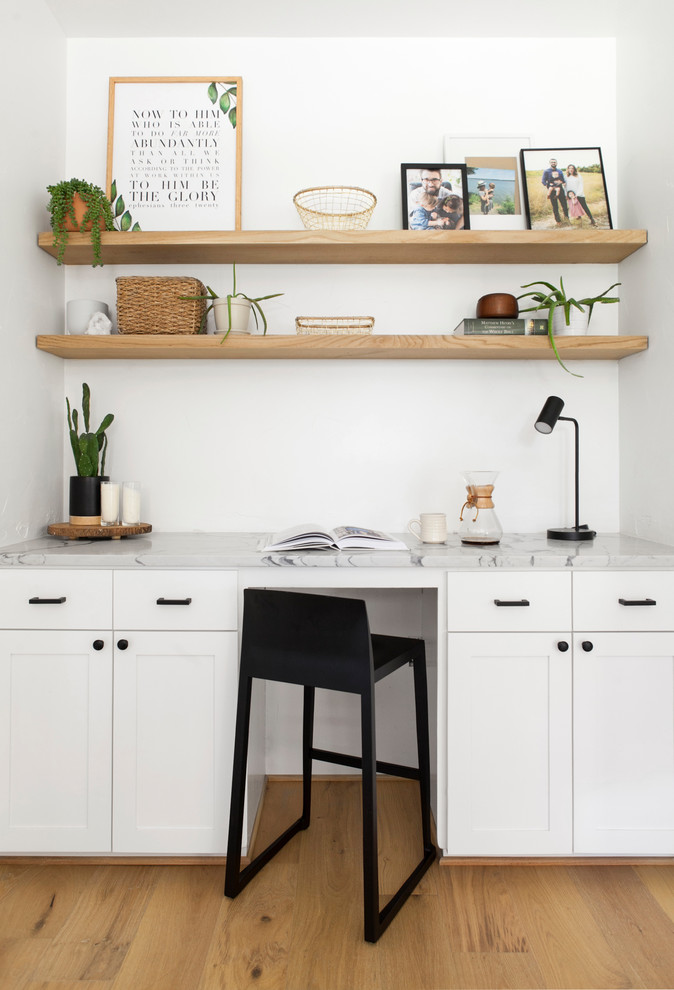 Kleines Skandinavisches Arbeitszimmer ohne Kamin mit Arbeitsplatz, weißer Wandfarbe, hellem Holzboden, Einbau-Schreibtisch und beigem Boden in Dallas