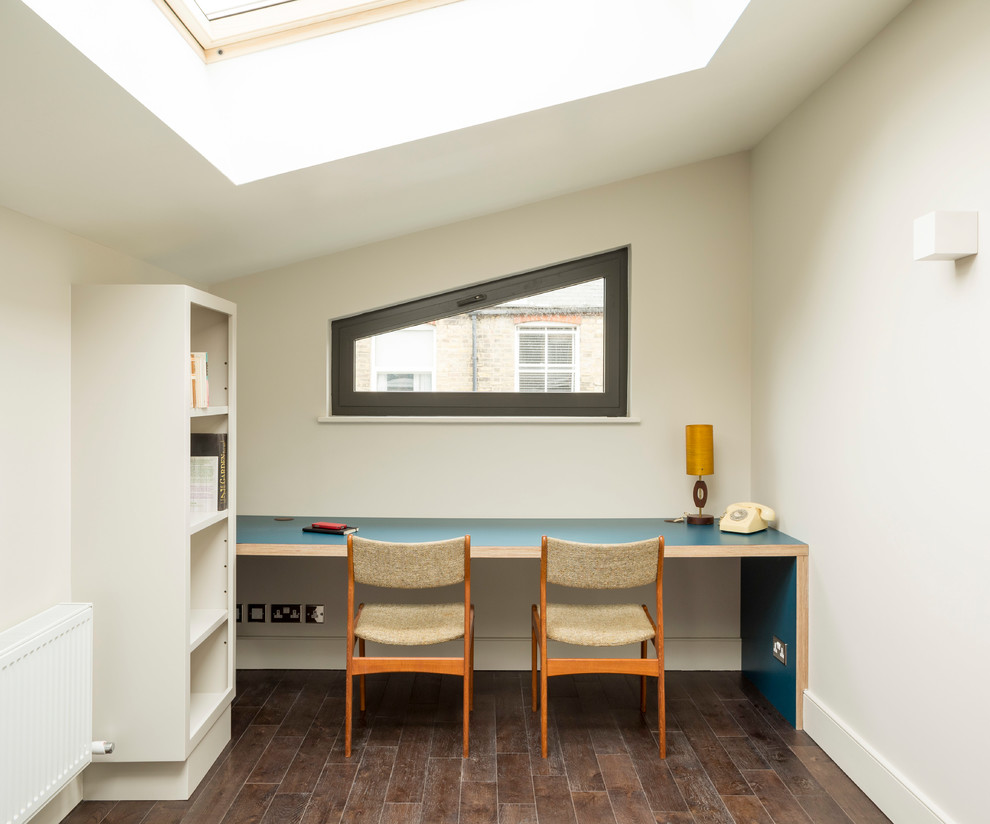 Photo of a medium sized contemporary study in London with dark hardwood flooring, a built-in desk and brown floors.