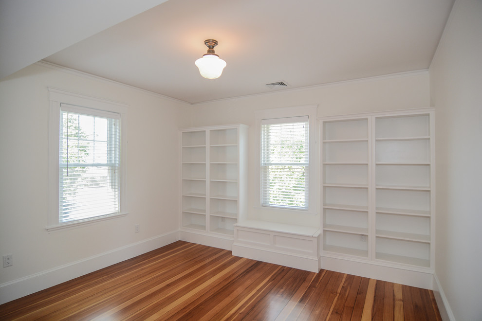 Diseño de despacho tradicional renovado de tamaño medio con biblioteca, paredes blancas, suelo de madera en tonos medios y escritorio independiente